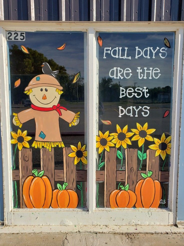 two windows decorated with pumpkins and scarecrows