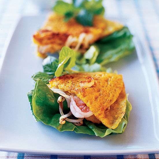 two small sandwiches are on a white plate with lettuce and tomato toppings