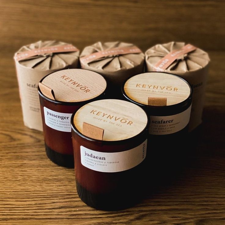 four candles sitting on top of a wooden table next to each other with labels on them