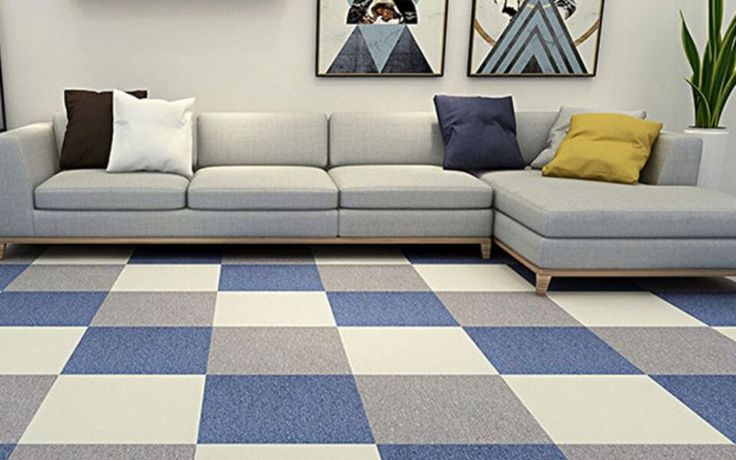 a living room with blue and white checkered carpeting on the floor, two pictures hanging above the couch