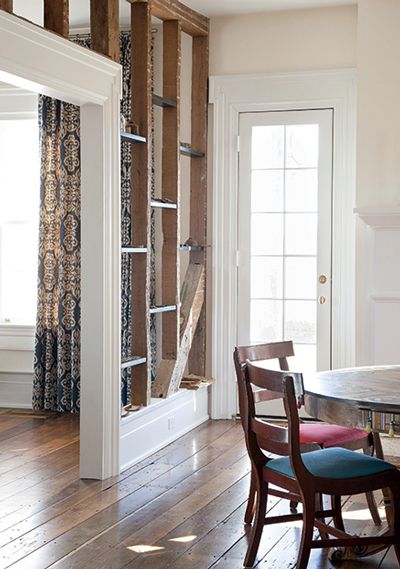 a dining room table and chairs in front of a doorway with wood beams on the wall