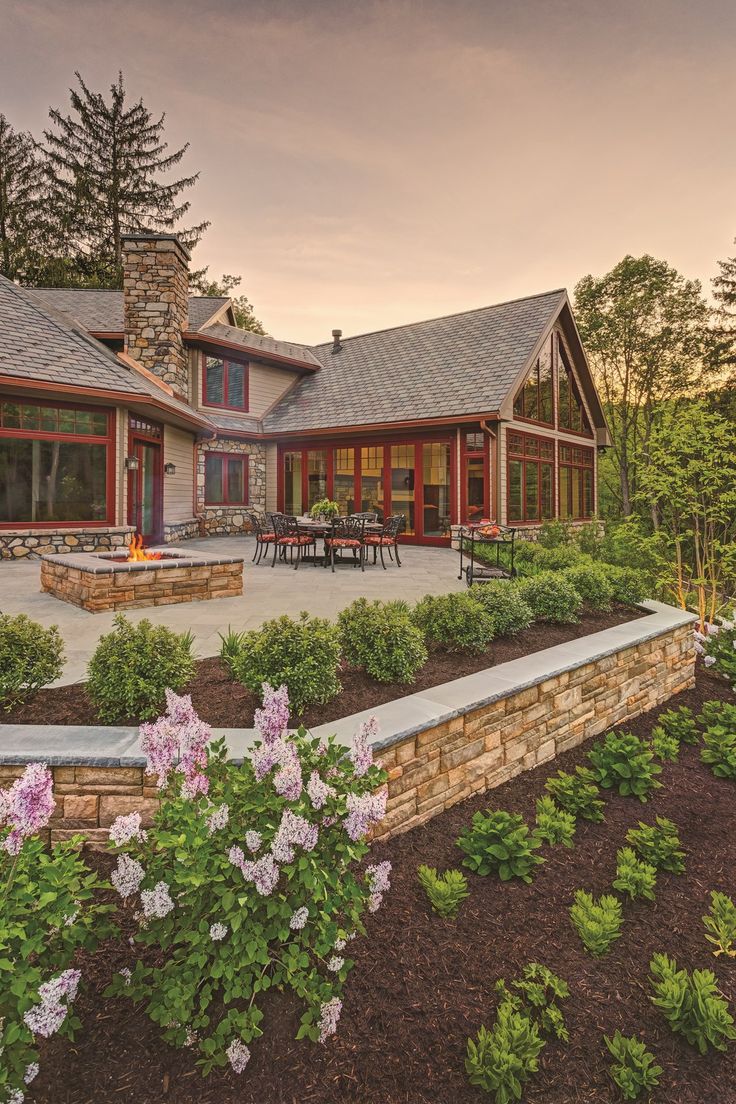 a large house with landscaping around it and flowers in the foreground, at sunset