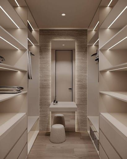 an empty walk in closet with white shelves and lights on the ceiling, along with a sink