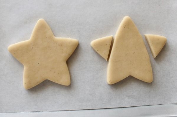 two cookies shaped like stars sitting on top of a baking sheet next to each other