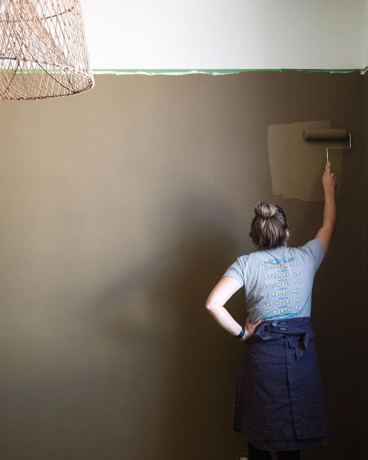 a woman is painting the wall in her home