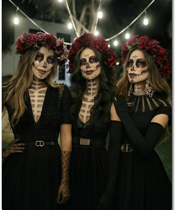 three women dressed up in skeleton makeup and flowers on their heads are standing next to each other