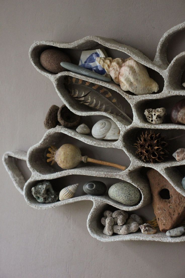 there is a wall shelf made out of rocks and stones with shells in them on it