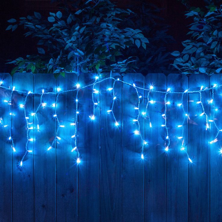 a fence with blue lights hanging from it's sides in front of a tree