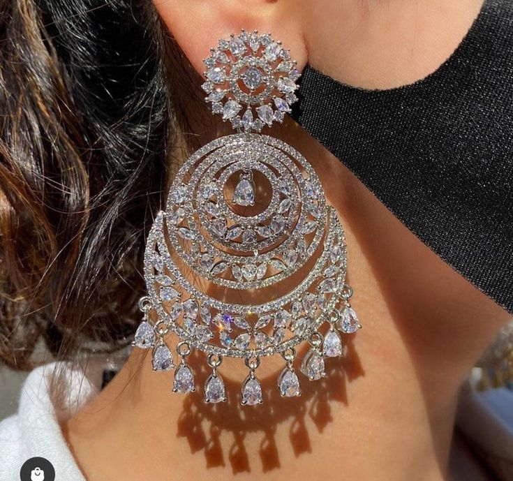 a close up of a woman's ear wearing large earrings with diamonds on them