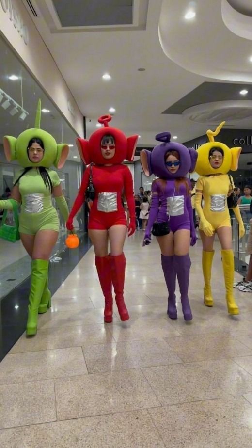 four women in costumes are walking down the hall together, all dressed up like cartoon characters