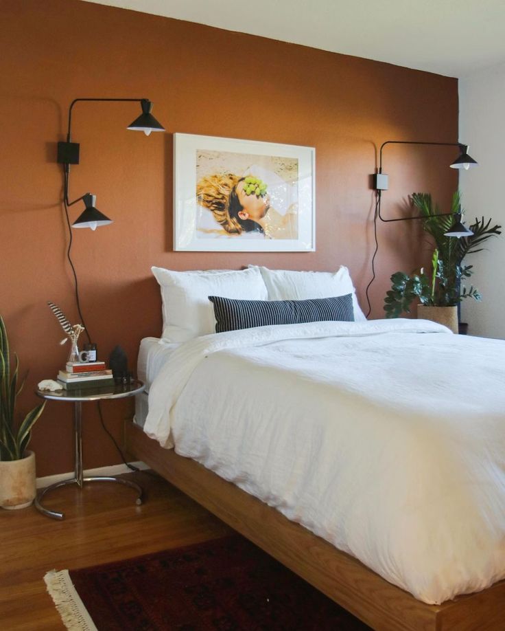 a bed sitting in a bedroom next to a wall mounted plant and a painting on the wall