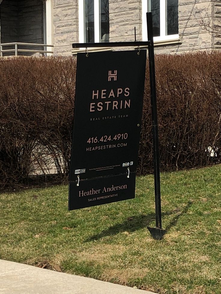 a black sign sitting on the side of a road next to a grass covered field