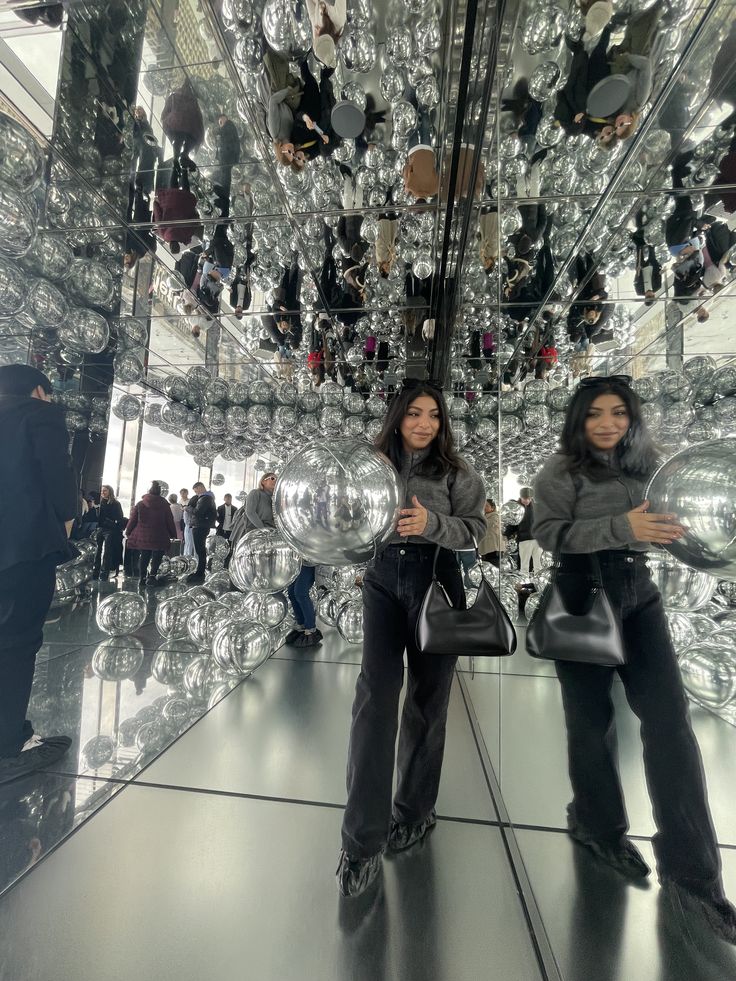 two women standing in front of a large mirror ball with lots of mirrors hanging from it