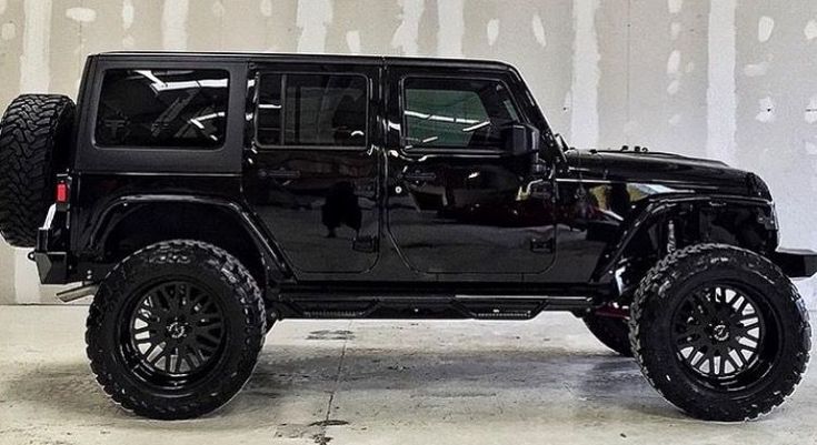 a black jeep parked in front of a white wall