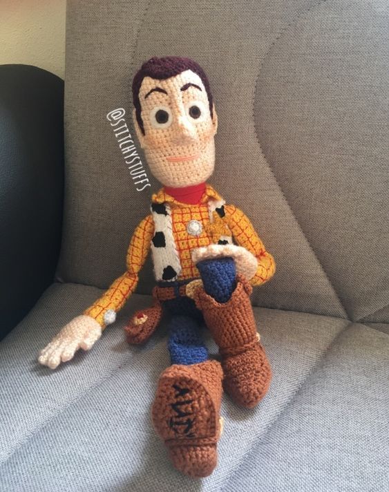 a crocheted toy sitting on top of a gray couch