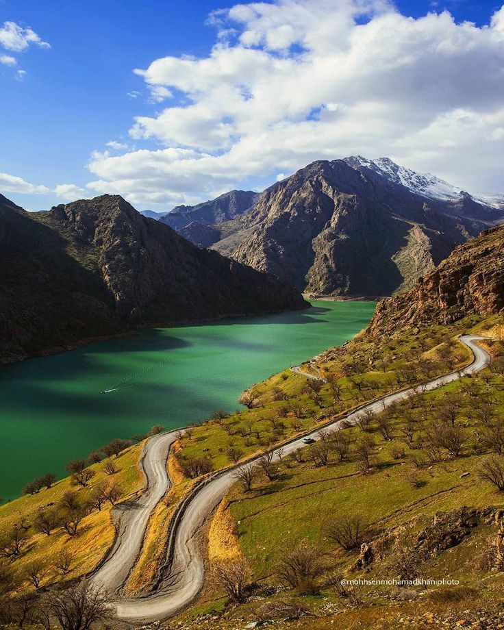 a winding road in the mountains leading to a lake