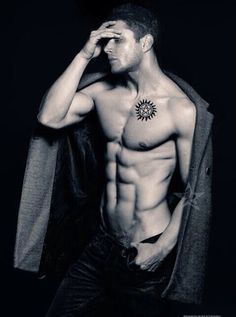 a shirtless man is holding his jacket over his head and looking at the camera