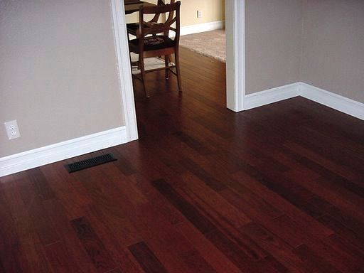 an empty room with hard wood flooring and a dining table in the corner between two walls