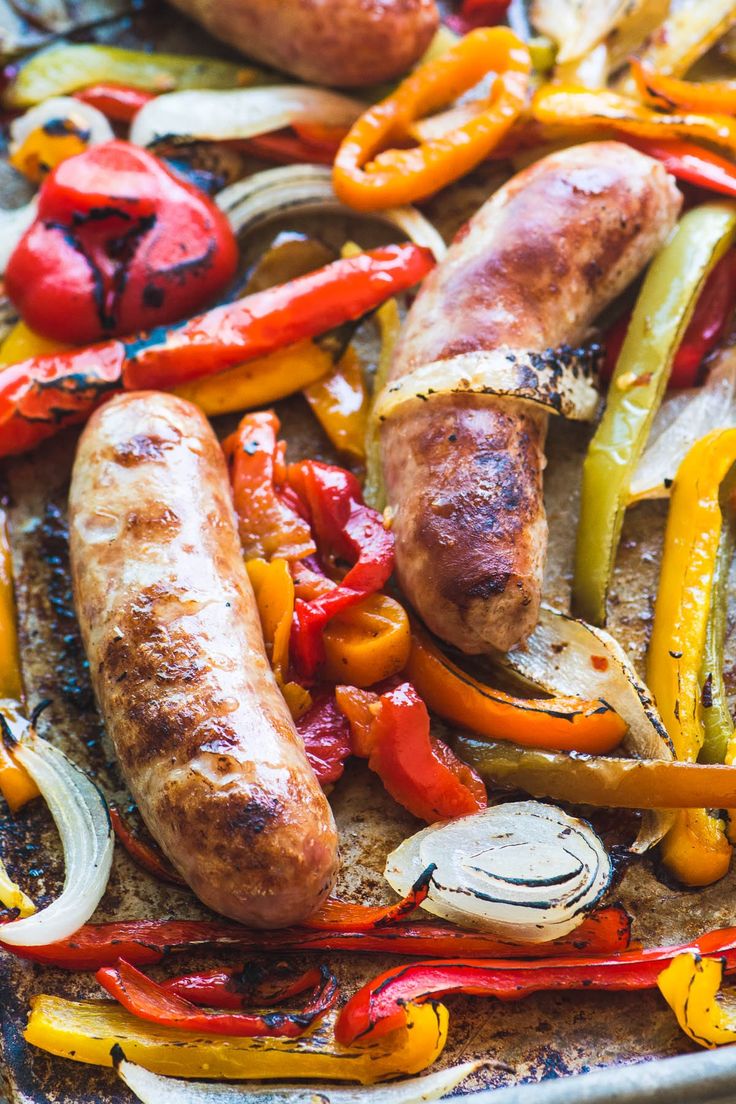 sausages, peppers and onions on a baking sheet