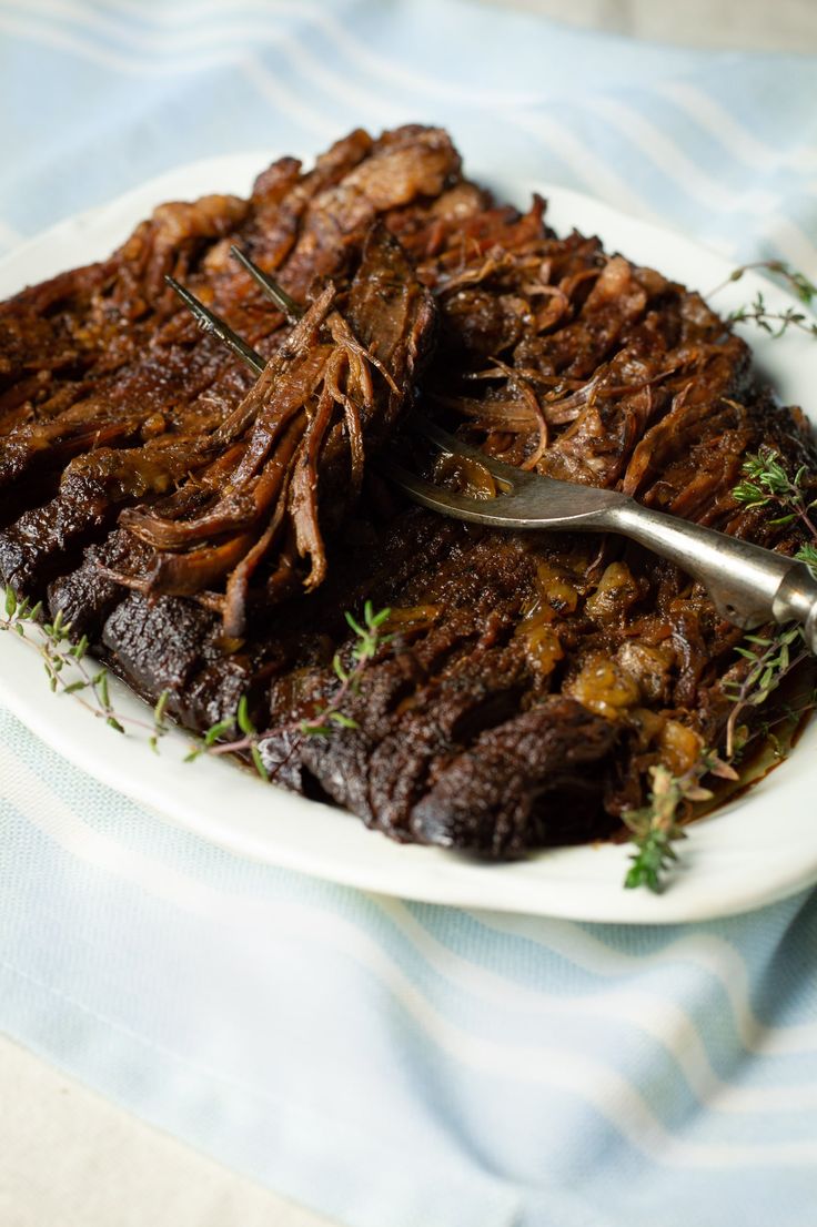 a white plate topped with meat and garnish on top of a blue table cloth