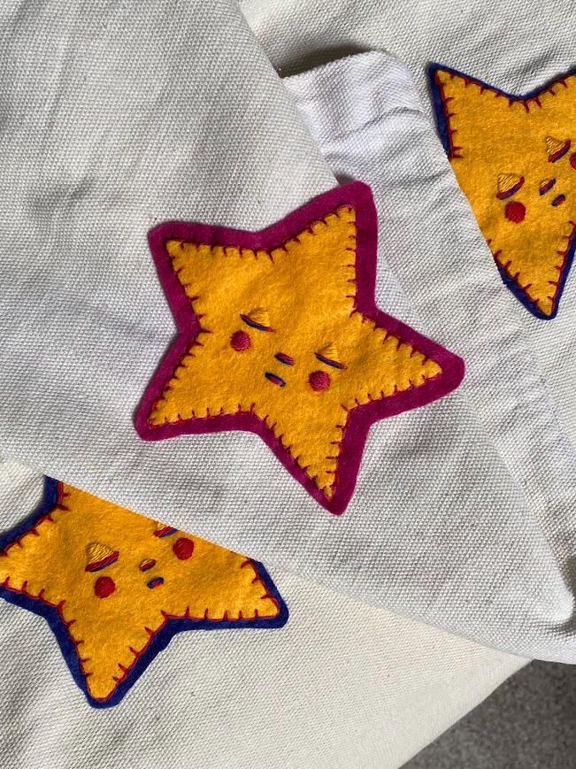 two yellow and red stars are on white fabric, one is embroidered onto the other