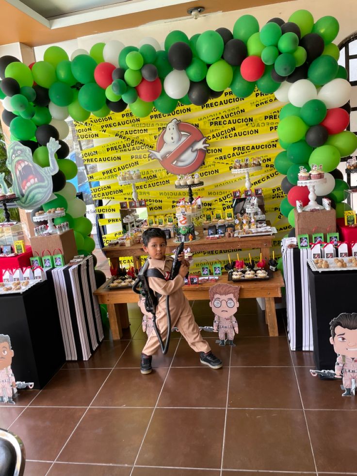 a young boy standing in front of a table filled with balloons and paper animals on it