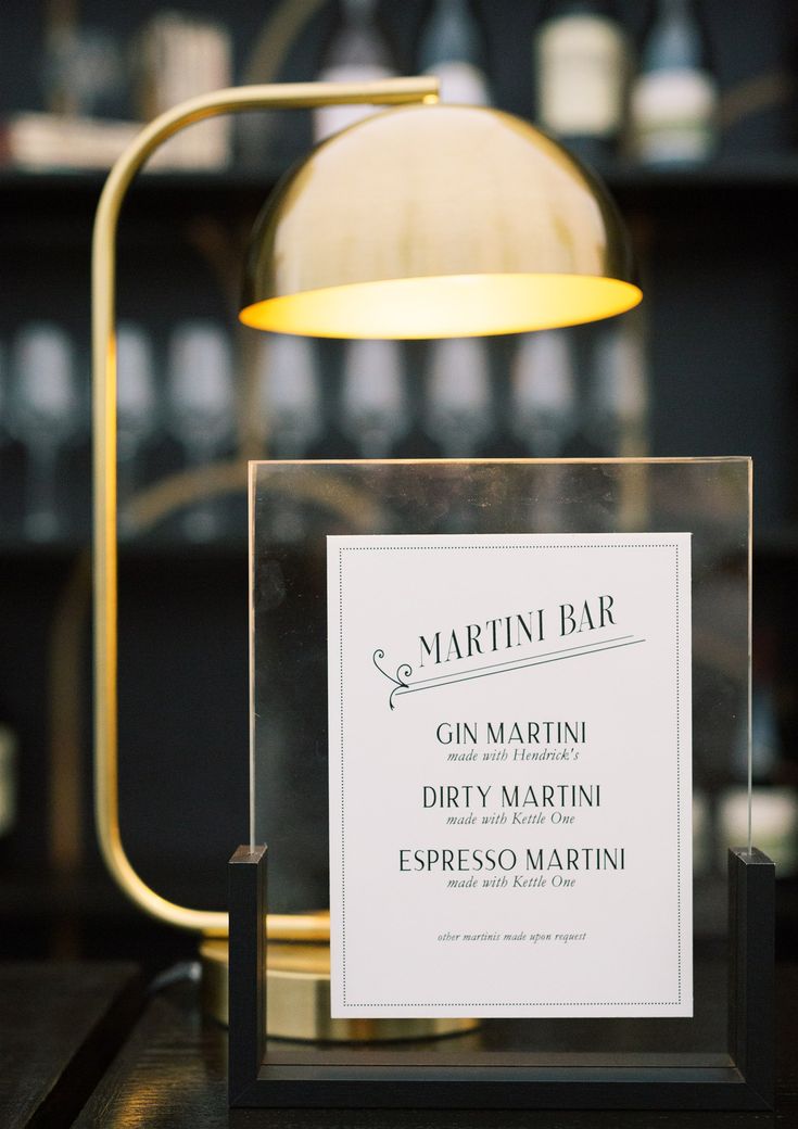 there is a sign that says martini bar on the table in front of a lamp