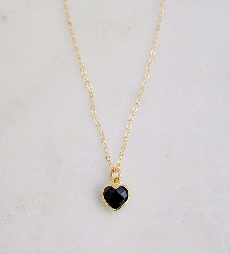 "Crafted onto a 14k gold filled chain and set in 24k gold electroplate, this black onyx heart is as precious as the affection it symbolizes. Make it that perfect gift for someone special, including yourself! Exuding protective and calming energies, Black Onyx is associated with the root chakra. It's believed to be an \"anti-panic\" stone which soothes stress and helps clear mental confusion and hyperactivity. GEMSTONE: Black Onyx STONE SIZE: average 10mm (.39\")  STONE SHAPE: Faceted Heart (Hear Black Heart-shaped Jewelry For Anniversary, Black Enamel Necklace For Anniversary, Black Necklaces For Anniversary On Valentine's Day, Black Necklace For Anniversary On Valentine's Day, Valentine's Day Black Necklace For Anniversary, Black Jewelry For Valentine's Day Gift, Black Heart Shaped Jewelry With Adjustable Chain, Black Heart-shaped Jewelry With Adjustable Chain, Elegant Black Heart Necklace With Adjustable Chain