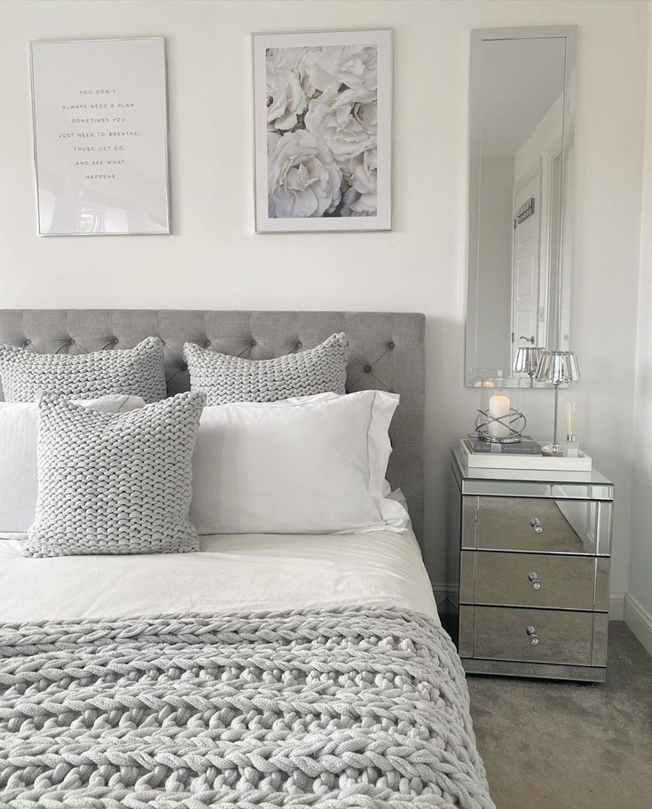 a bed with white sheets and pillows in front of two pictures on the wall above it