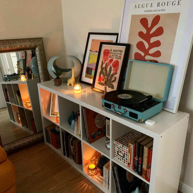 there is a book shelf with many books and pictures on it, along with a record player