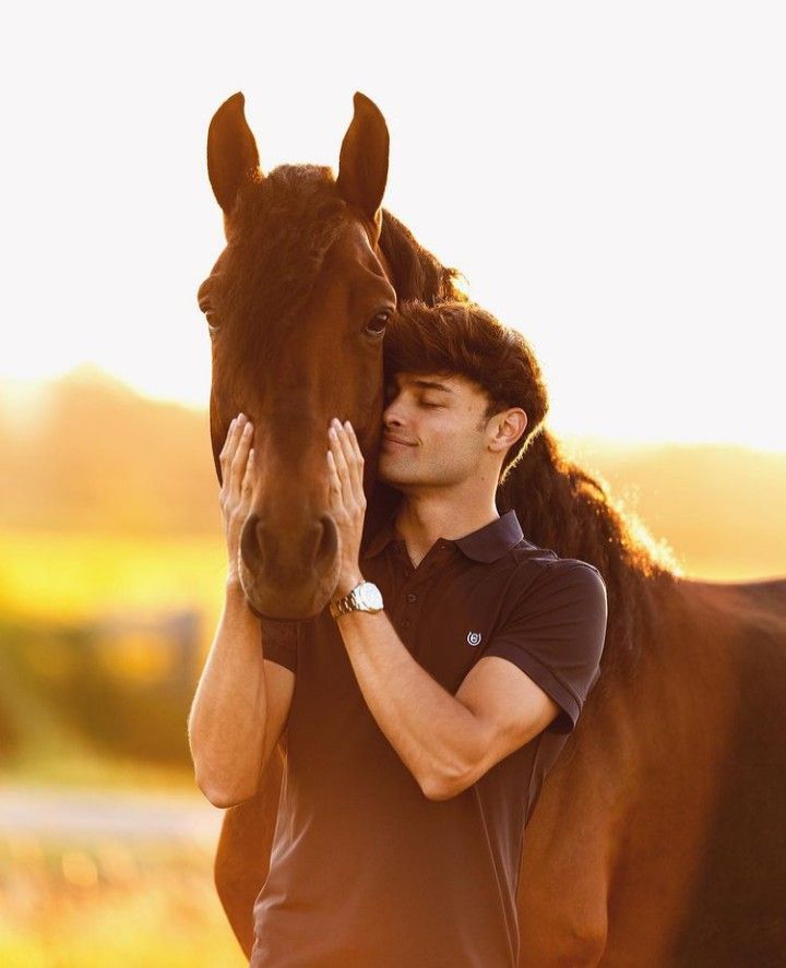 a man holding the head of a brown horse with his hands on it's face