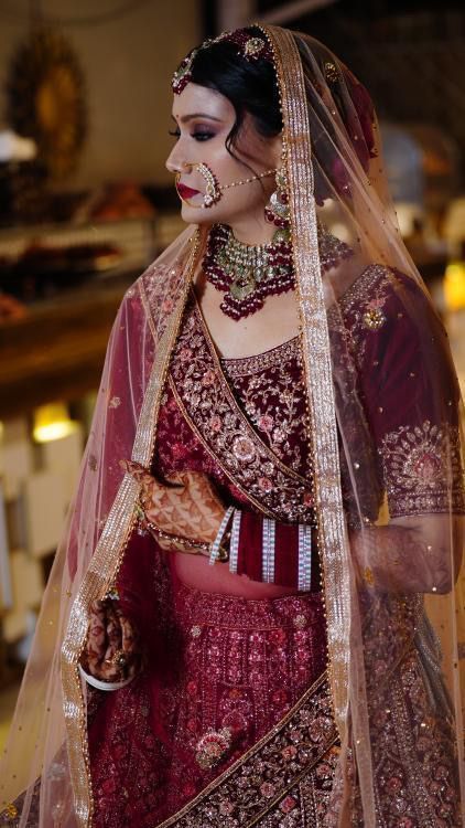 a woman wearing a red and gold bridal outfit