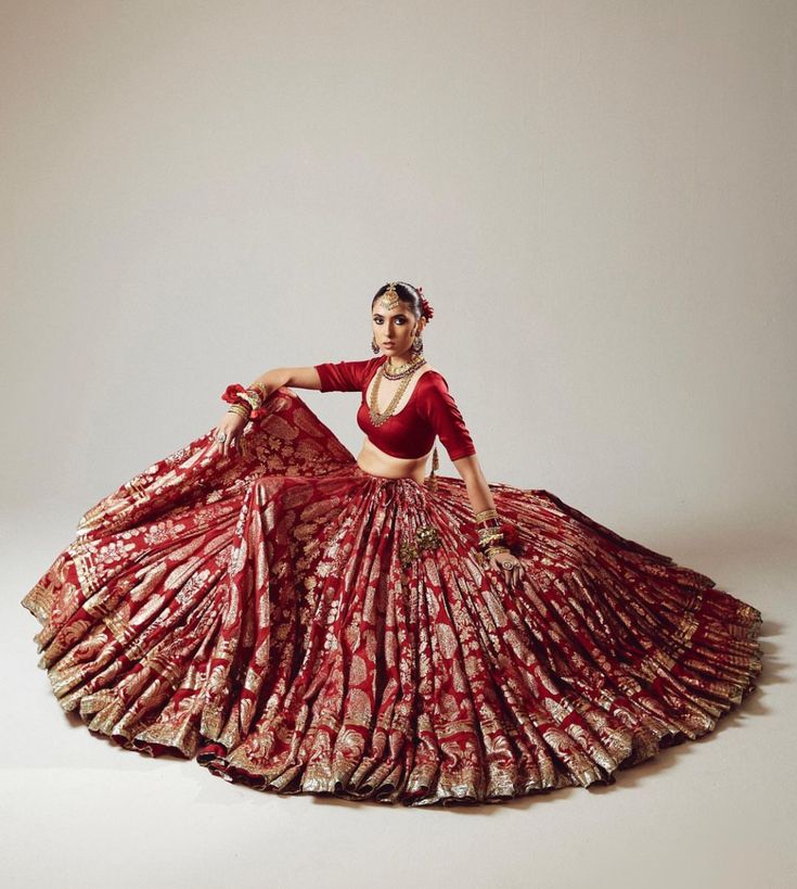 a woman in a red and gold dress is sitting on the floor with her arms outstretched