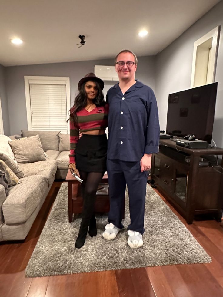 a man and woman standing next to each other in front of a tv set on top of a hard wood floor