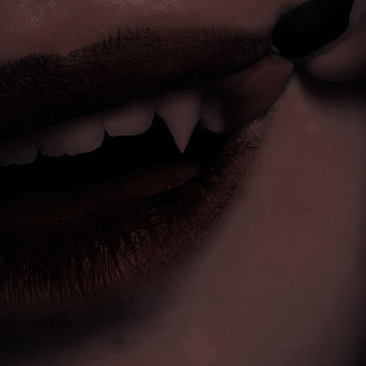 a woman's mouth with white teeth and dark makeup is shown in this image