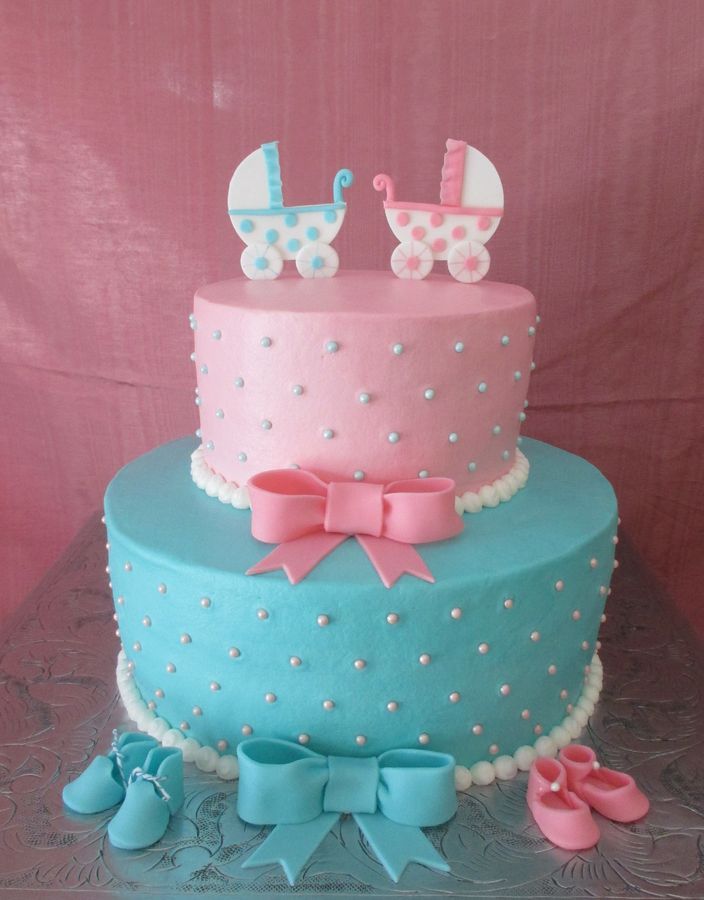 a blue and pink cake with baby carriage decorations