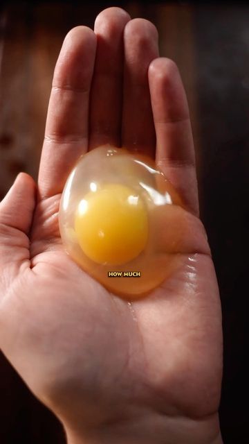 a hand holding an egg in it's palm with water droplets on the top