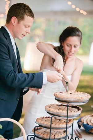 a bride and groom cutting their wedding cake at the reception table with pies on it