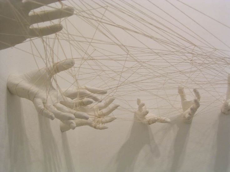 several hands are attached to strings in the air with white paint on them and one hand is reaching up