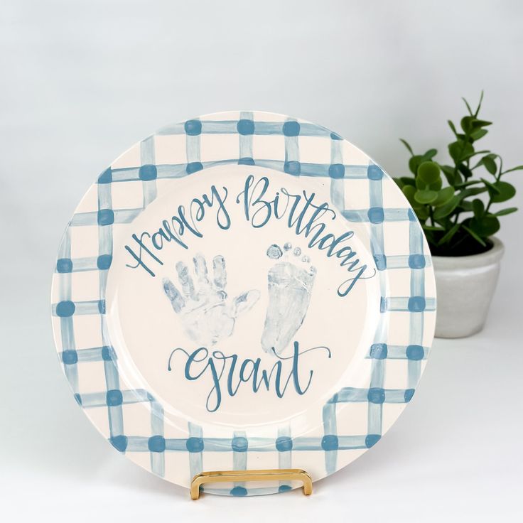 a blue and white plate that says happy birthday grant with handprints on it