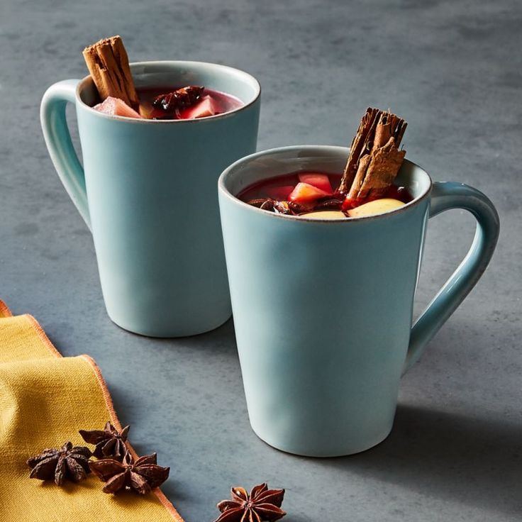 two blue mugs filled with hot chocolate and cinnamon stick garnished with star anise