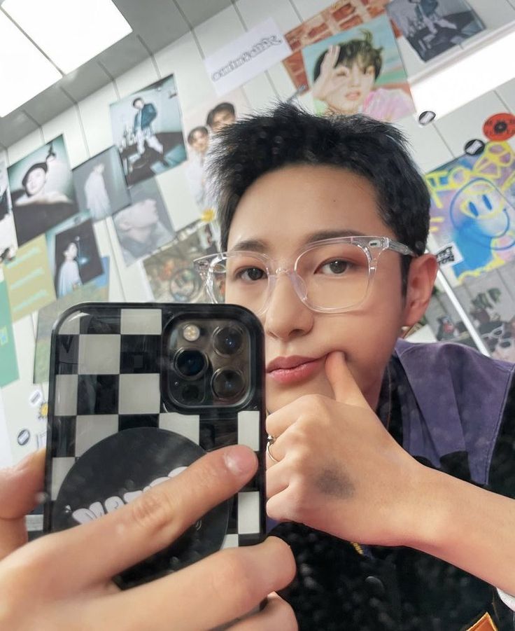 a man taking a selfie with his cell phone in front of him and wearing glasses