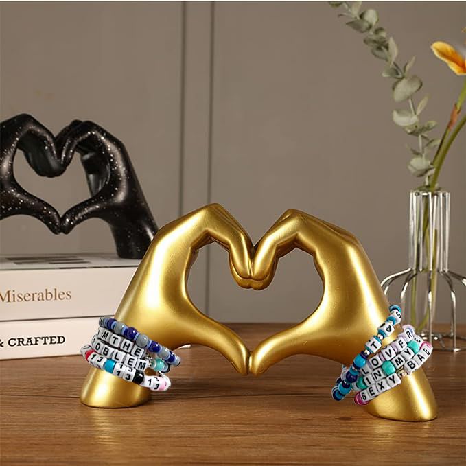 two gold heart shaped objects sitting on top of a wooden table next to books and vases