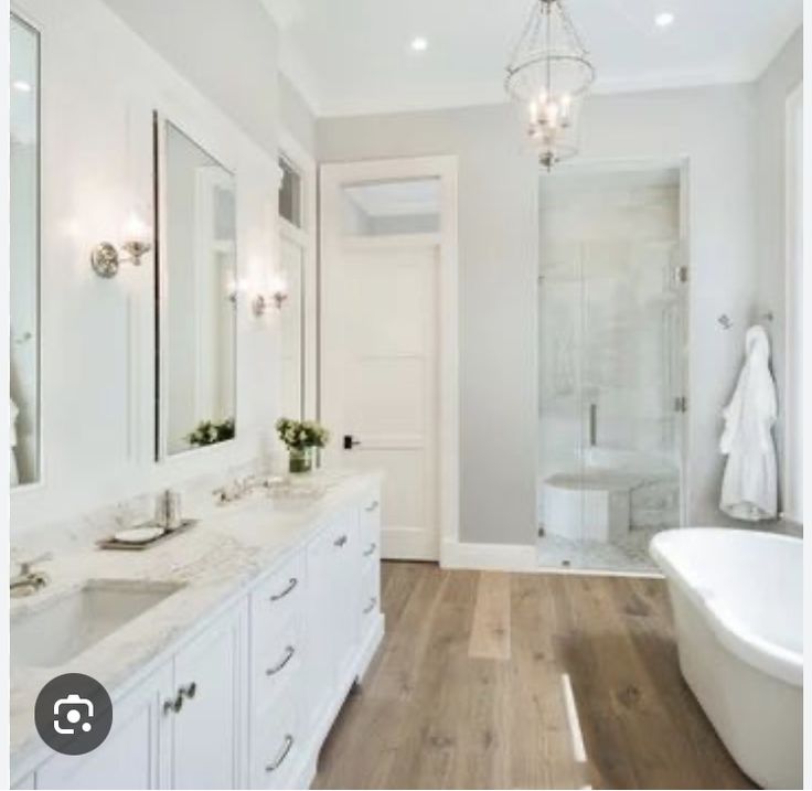 a large bathroom with white fixtures and wood floors