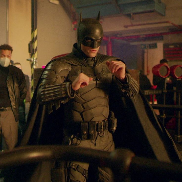 a man dressed as batman standing next to another man