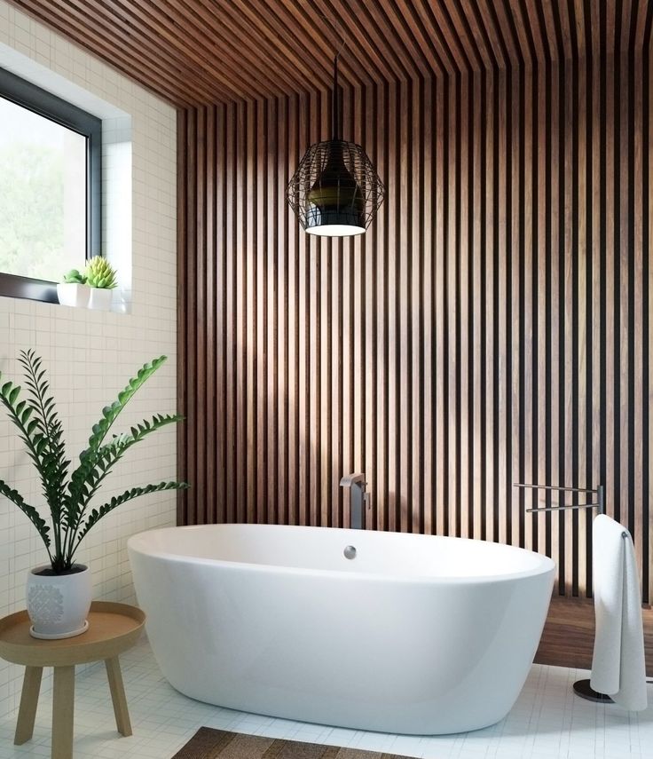 a large white bath tub sitting next to a plant in a bathroom under a window