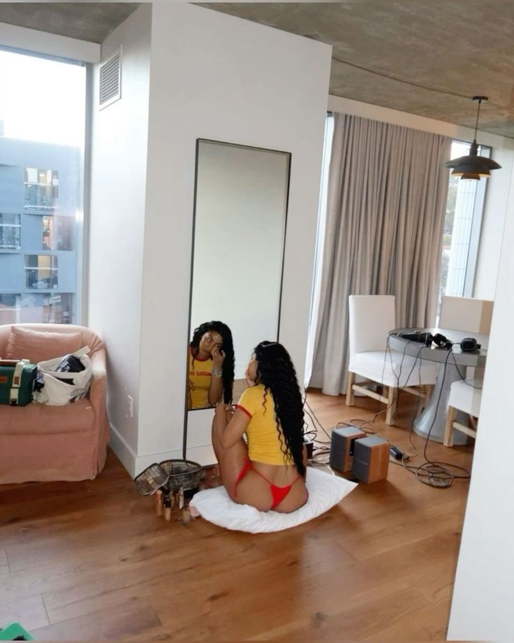 a woman sitting on the floor in front of a mirror