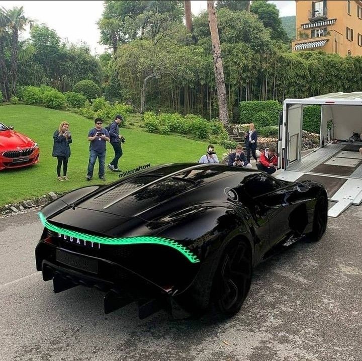 a futuristic car is parked on the side of the road as people look at it