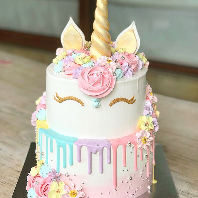 a cake decorated with pastel flowers and unicorn horns on top of a wooden table