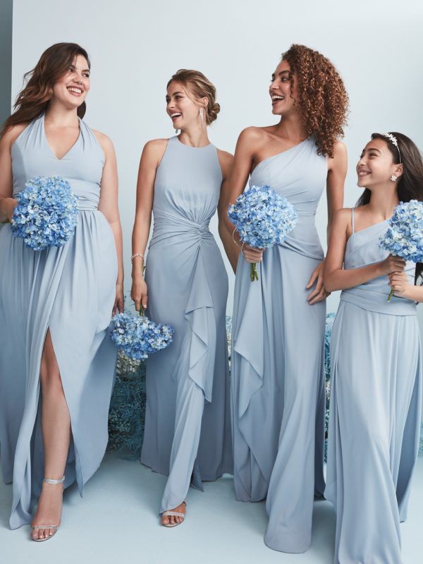 four bridesmaids in light blue dresses laughing and posing for the camera with their bouquets